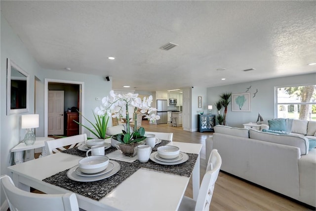 dining room with a textured ceiling and light hardwood / wood-style flooring