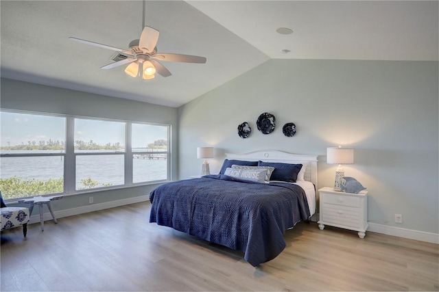 bedroom with light hardwood / wood-style flooring, vaulted ceiling, ceiling fan, and a water view