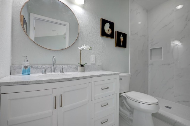 bathroom with vanity, toilet, and a tile shower