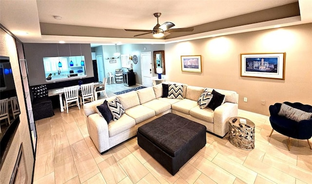 living room with a tray ceiling and ceiling fan