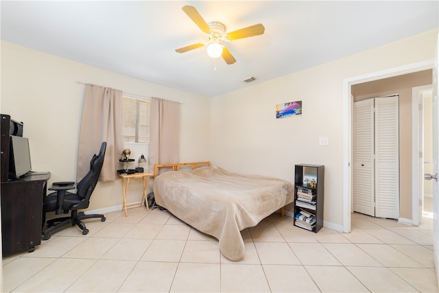 tiled bedroom with ceiling fan and a closet