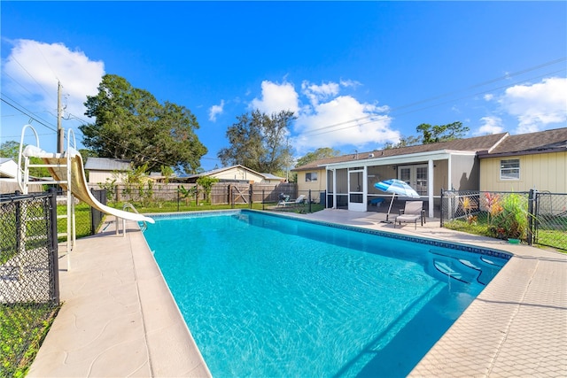 view of swimming pool with a patio, a sunroom, and a water slide