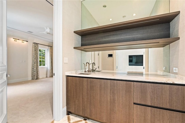 kitchen featuring open shelves, a sink, carpet flooring, baseboards, and light stone countertops