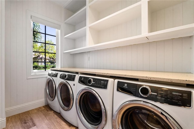 washroom featuring laundry area, baseboards, light wood-style floors, and separate washer and dryer