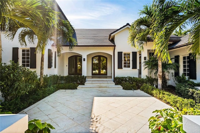 property entrance featuring stucco siding and french doors