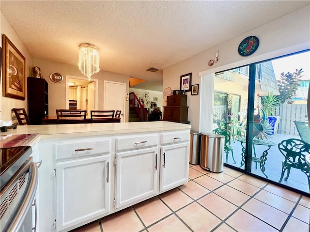 kitchen featuring white cabinetry, light tile patterned floors, a textured ceiling, and electric stove