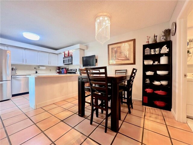 tiled dining space featuring an inviting chandelier and a textured ceiling