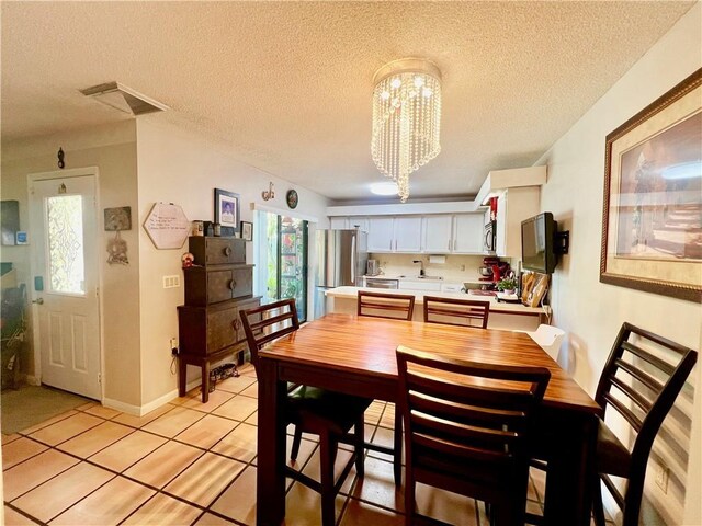 tiled dining room with an inviting chandelier and a textured ceiling