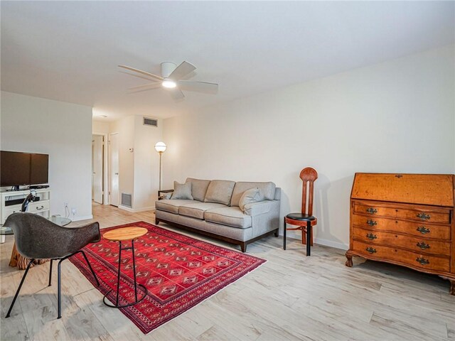 living room featuring a ceiling fan, baseboards, visible vents, and wood finished floors