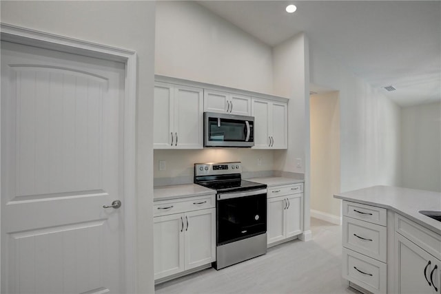 kitchen with white cabinets, light hardwood / wood-style floors, and appliances with stainless steel finishes