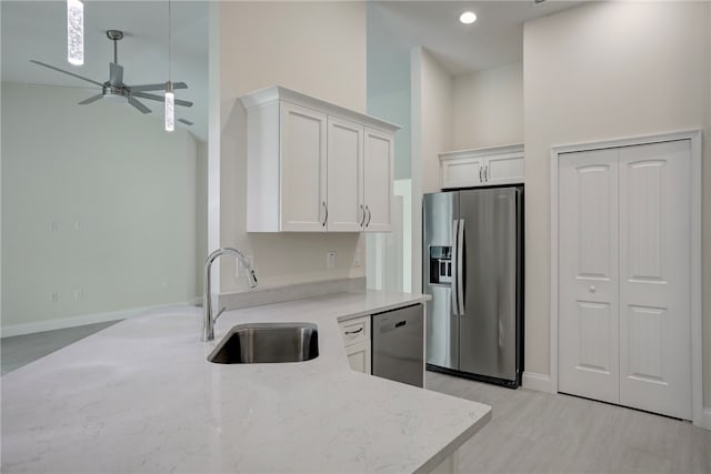 kitchen with sink, ceiling fan, a towering ceiling, appliances with stainless steel finishes, and white cabinetry