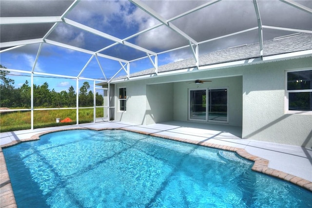 view of swimming pool featuring glass enclosure, ceiling fan, and a patio area