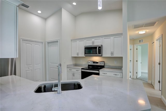 kitchen featuring light stone counters, sink, high vaulted ceiling, and appliances with stainless steel finishes