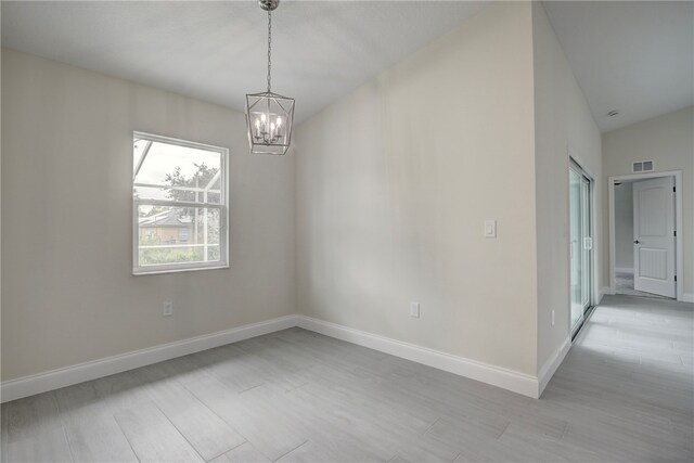 empty room with light hardwood / wood-style floors, lofted ceiling, and an inviting chandelier