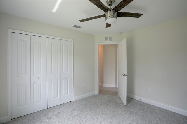 unfurnished bedroom featuring ceiling fan, a closet, and light carpet