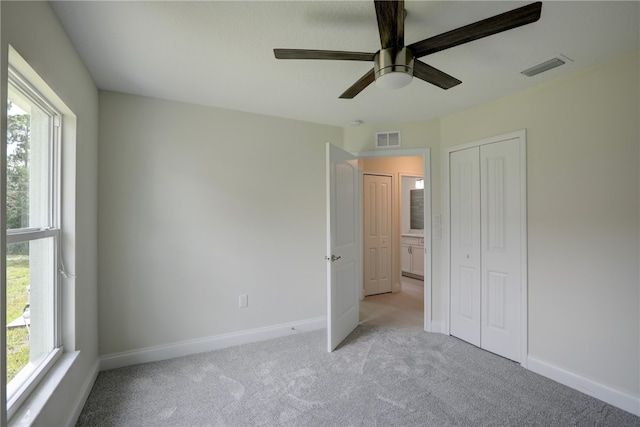 unfurnished bedroom with light carpet, a closet, and ceiling fan