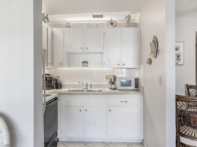 2800 Indian River Blvd Unit N2, Vero Beach, FL 32960 - kitchen featuring white microwave, electric range oven, a sink, white cabinets, and tasteful backsplash