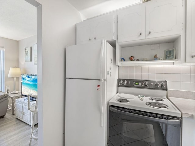 2800 Indian River Blvd Unit N2, Vero Beach, FL 32960 - kitchen with range with electric stovetop, freestanding refrigerator, white cabinets, and decorative backsplash