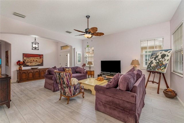 living room with ceiling fan with notable chandelier and light wood-type flooring