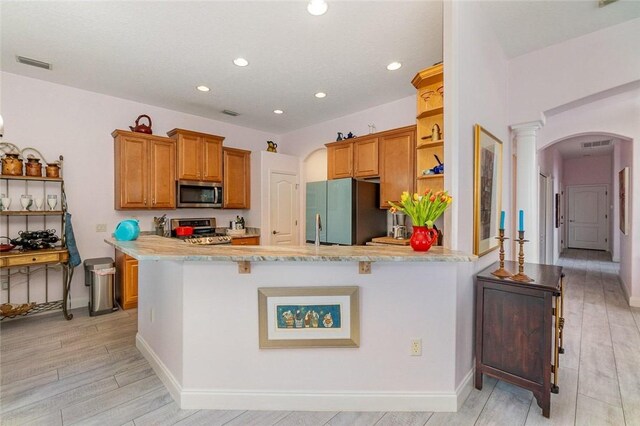 kitchen with kitchen peninsula, a kitchen breakfast bar, stainless steel appliances, and light hardwood / wood-style floors