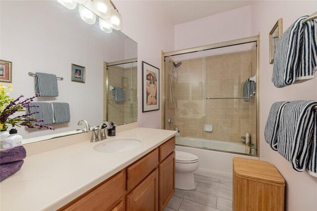 full bathroom with vanity, enclosed tub / shower combo, and toilet