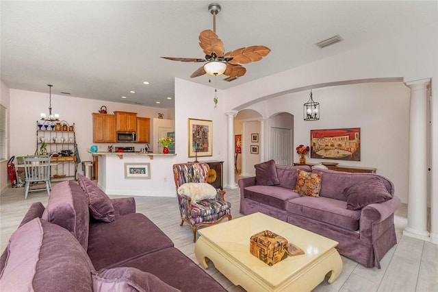 living room featuring ceiling fan with notable chandelier and decorative columns