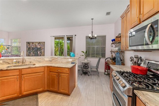 kitchen featuring light hardwood / wood-style floors, light stone counters, sink, and appliances with stainless steel finishes