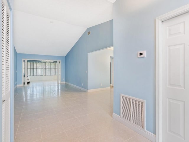 corridor featuring light tile patterned floors, lofted ceiling, visible vents, and baseboards