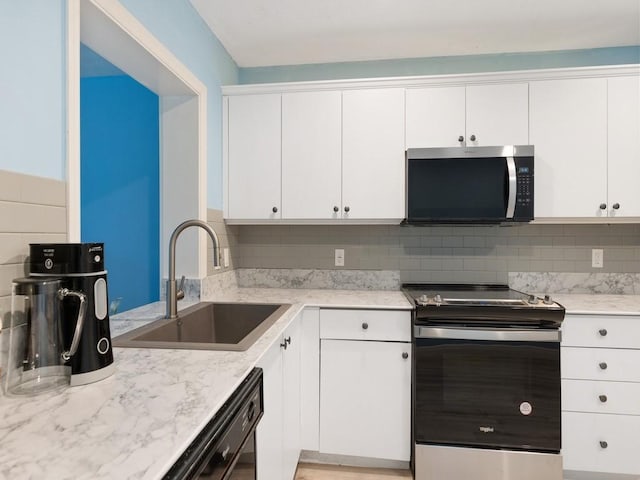 kitchen featuring white cabinets, tasteful backsplash, stainless steel appliances, and a sink