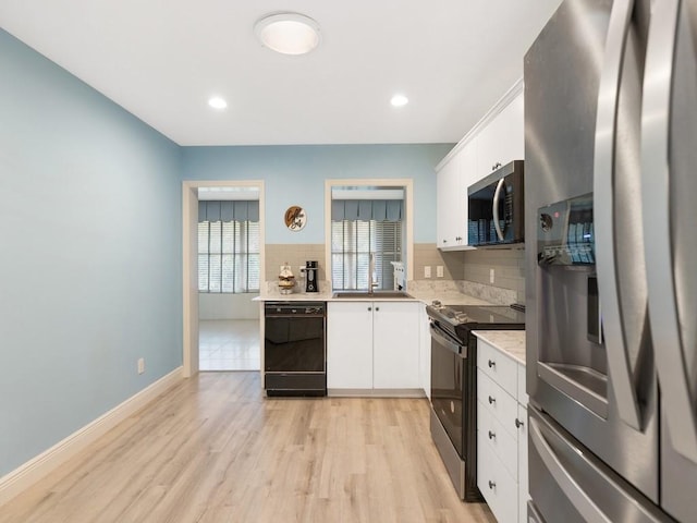 kitchen with decorative backsplash, stainless steel appliances, light countertops, light wood-type flooring, and white cabinetry