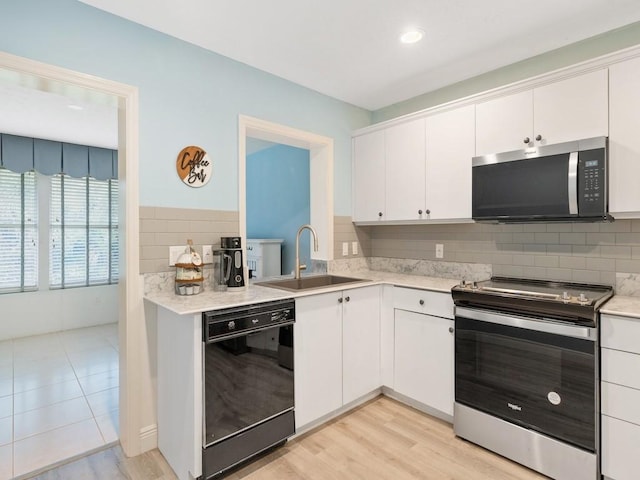 kitchen with appliances with stainless steel finishes, white cabinets, light countertops, and a sink