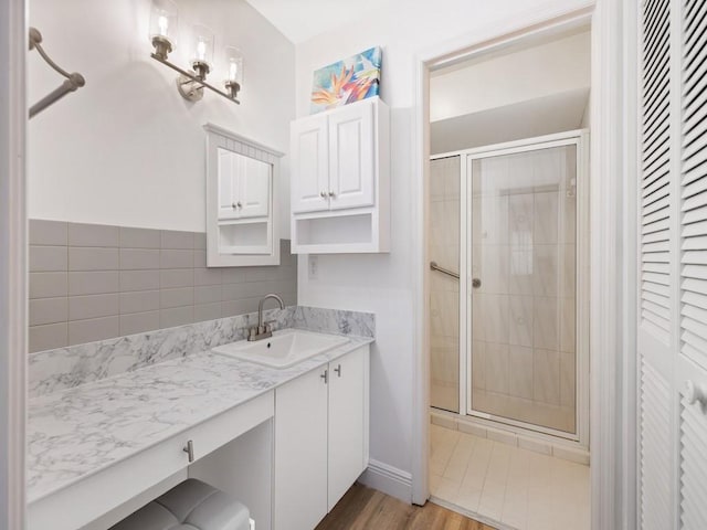 full bathroom with wood finished floors, a closet, a shower stall, and vanity