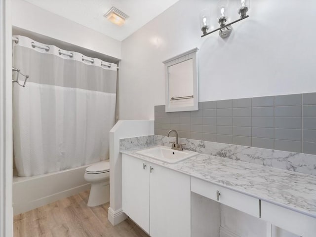 bathroom featuring toilet, shower / tub combo with curtain, wood finished floors, and vanity