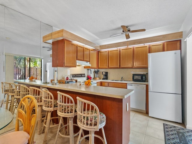 kitchen with kitchen peninsula, white appliances, a textured ceiling, and ceiling fan