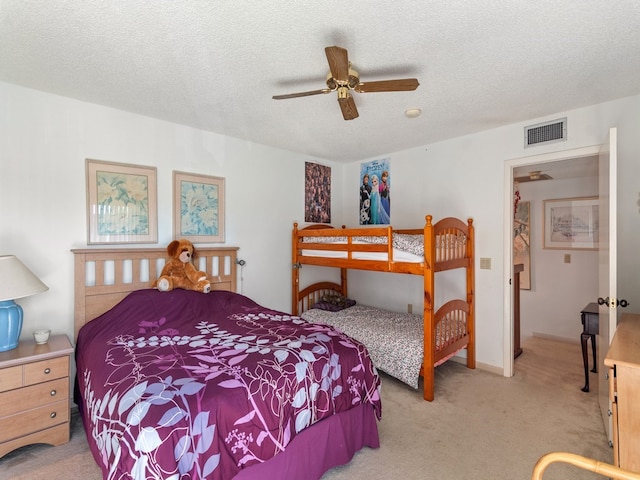 bedroom with a textured ceiling, light colored carpet, and ceiling fan