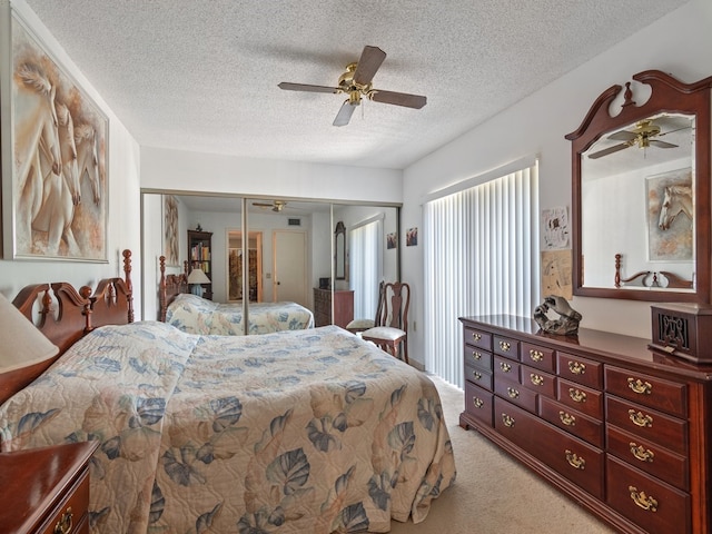 bedroom with a closet, a textured ceiling, light carpet, and ceiling fan