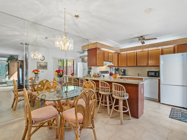 kitchen with pendant lighting, a textured ceiling, white appliances, and light tile patterned floors