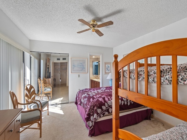 carpeted bedroom featuring ceiling fan, connected bathroom, a closet, and a textured ceiling