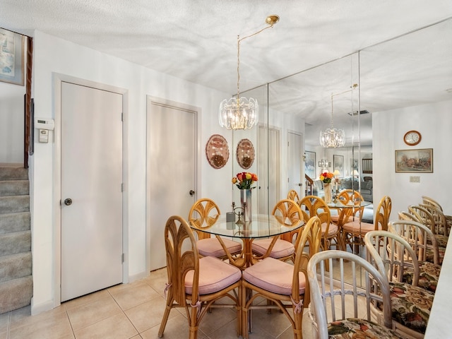 tiled dining room with a textured ceiling and an inviting chandelier