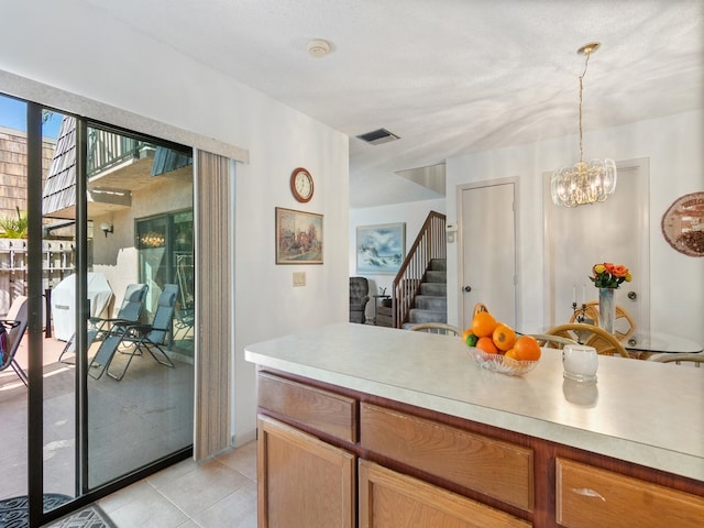 kitchen featuring pendant lighting, a textured ceiling, a notable chandelier, and light tile patterned floors