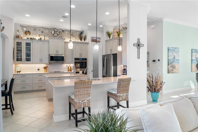 kitchen with crown molding, a breakfast bar area, stainless steel appliances, gray cabinets, and a sink