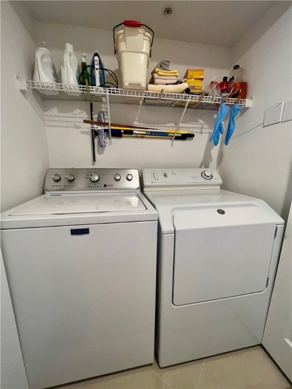 clothes washing area with separate washer and dryer and light tile patterned floors