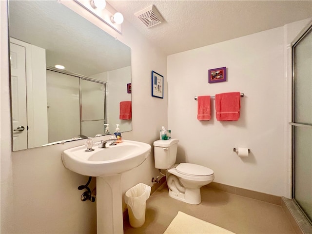 bathroom with toilet, sink, a textured ceiling, and a shower with door