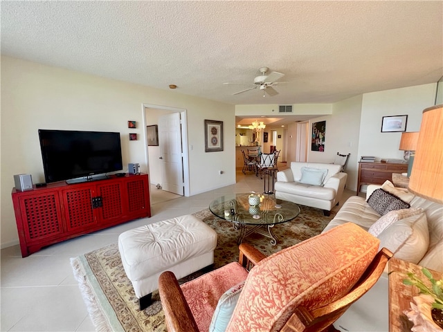 tiled living room with ceiling fan with notable chandelier and a textured ceiling