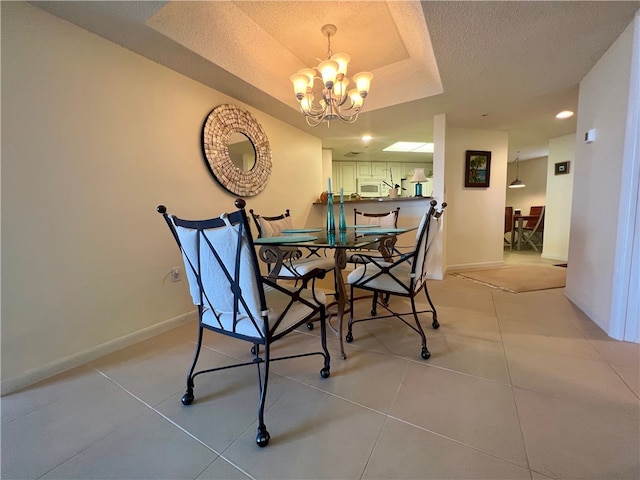 dining space featuring a chandelier, a tray ceiling, a textured ceiling, and light tile patterned floors