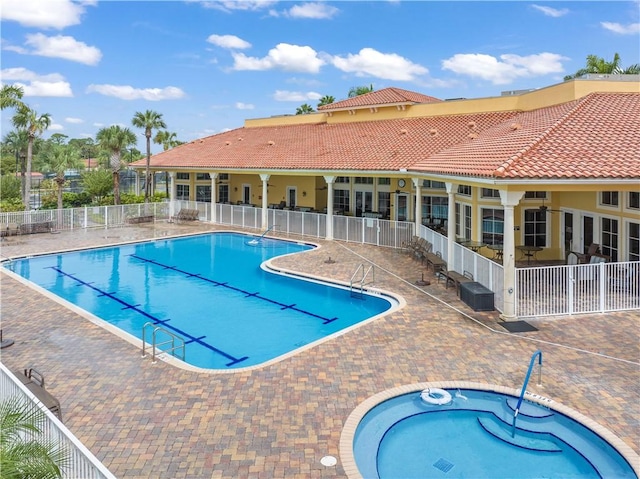 pool with a patio area, a hot tub, and fence