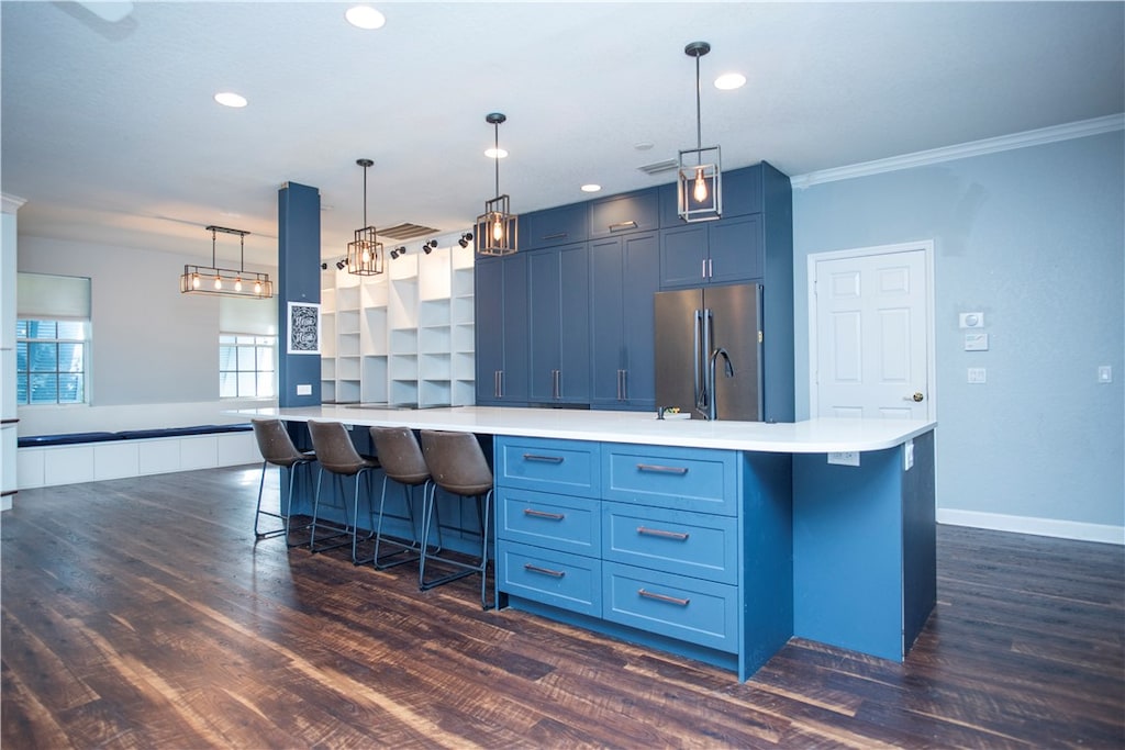 kitchen with a breakfast bar, crown molding, blue cabinetry, decorative light fixtures, and stainless steel refrigerator