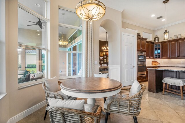 tiled dining room featuring ceiling fan with notable chandelier and ornamental molding