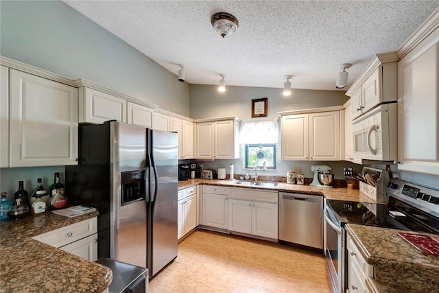 kitchen with sink, vaulted ceiling, stainless steel appliances, and a textured ceiling