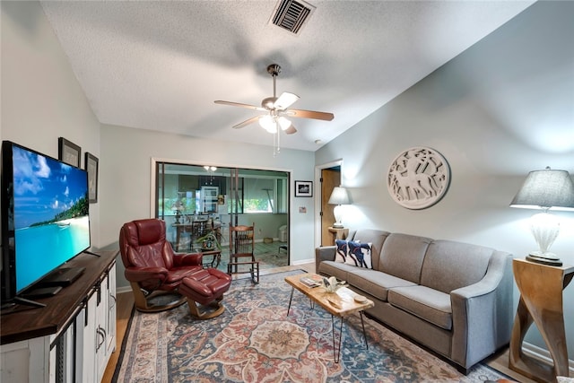 living room with ceiling fan and a textured ceiling